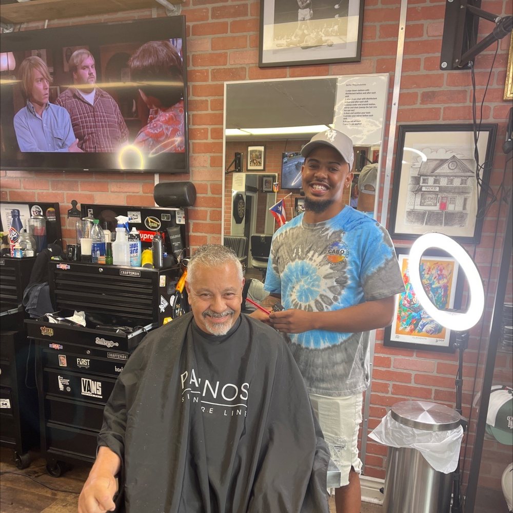 Barber finishing a haircut for a smiling client at Faded Barber Shop